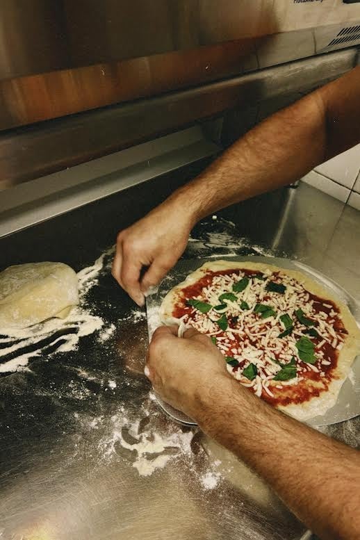 Préparation d'une pizza au restaurant Marinelli